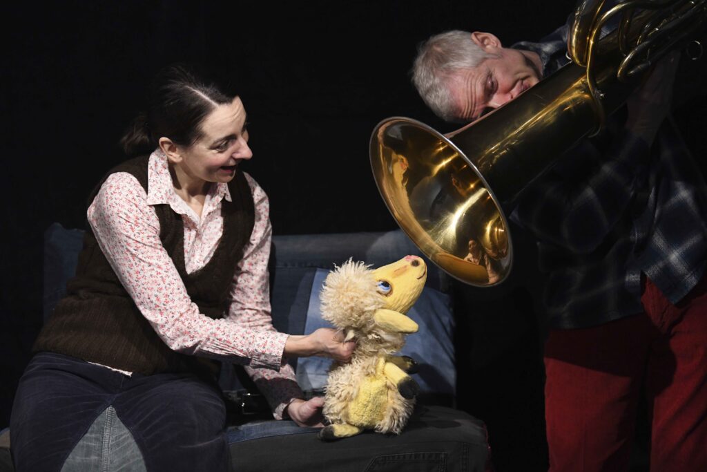 Schafpuppe Lotta schaut in den Trichter einer Tuba.